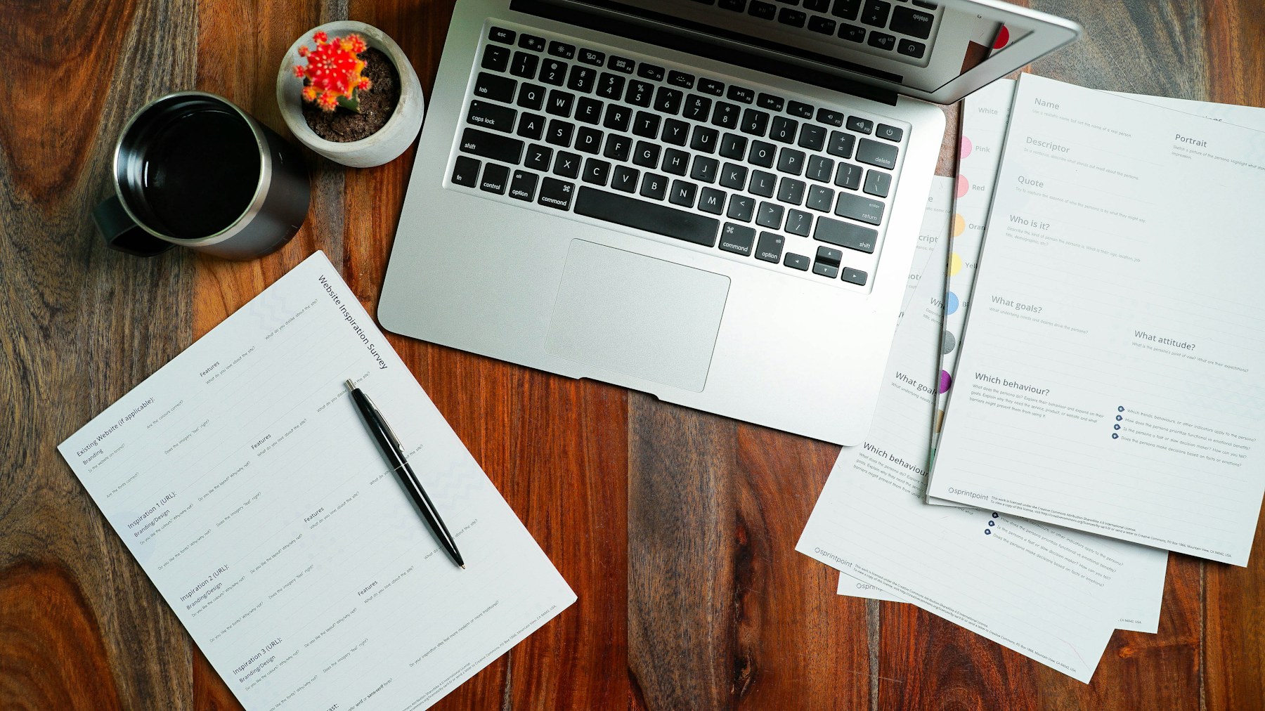 Laptop, notes and printed planning documents arranged on a desk.