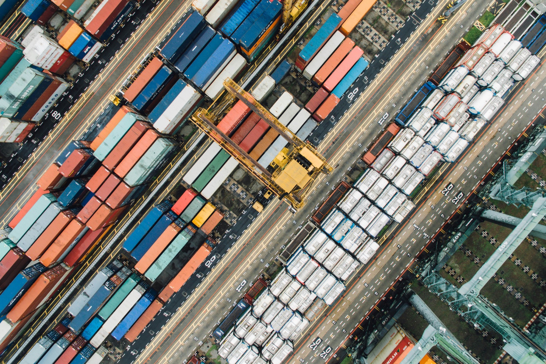 Aerial view of shipping containers and port logistics lanes.